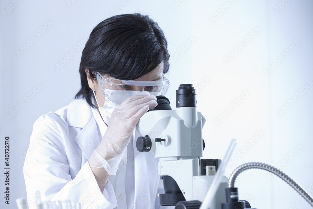 Female Lab technician looking through microscope Female Lab technician looking through microscope
