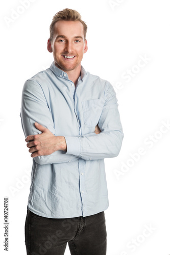 An attractive man wearing a light blue shirt and dark jeans with a big toothy smile. Standing against a white background.