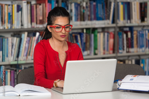 Happy Female Student With Laptop In Library