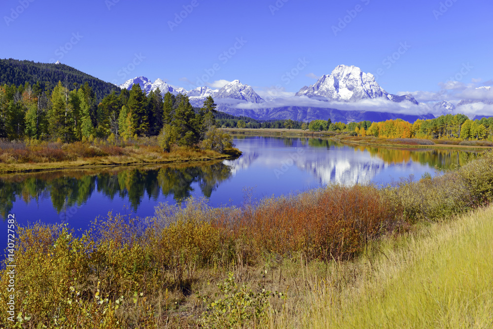 Autumn foliage in the Teton Range with reflection in calm water, Rocky Mountains, Wyoming, a popular destination for RV trips.