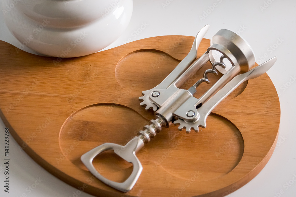 silver corkscrew. View from above over white wooden table background. wooden plate silver corkscrew. View from above over white wooden table background. wooden plate