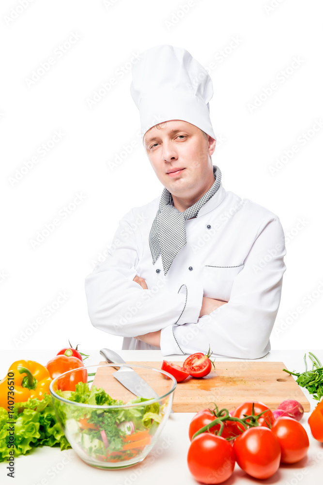 Vertical portrait of a cook at the table with vegetables on a white background Vertical portrait of a cook at the table with vegetables on a white background
