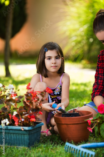 Young girl helping young woman gardening and using garden tools