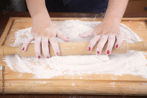 Woman rolling dough with rolling pin.