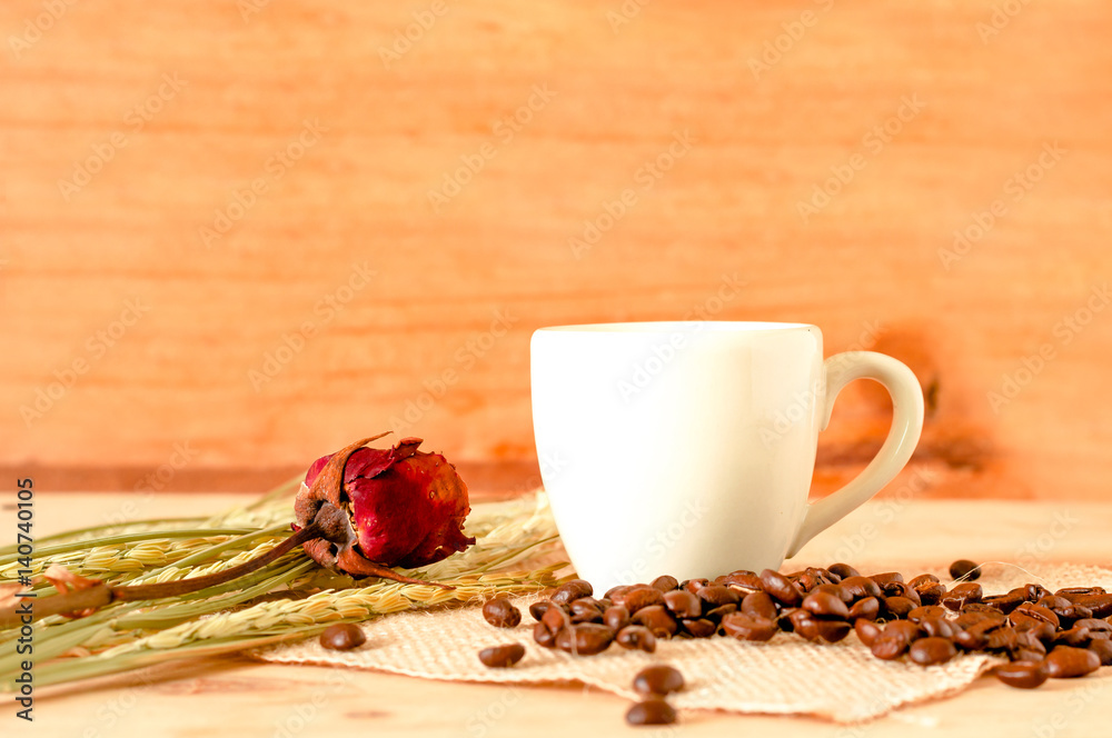 the hot coffee in the white cup on wooden table with coffee beans seed