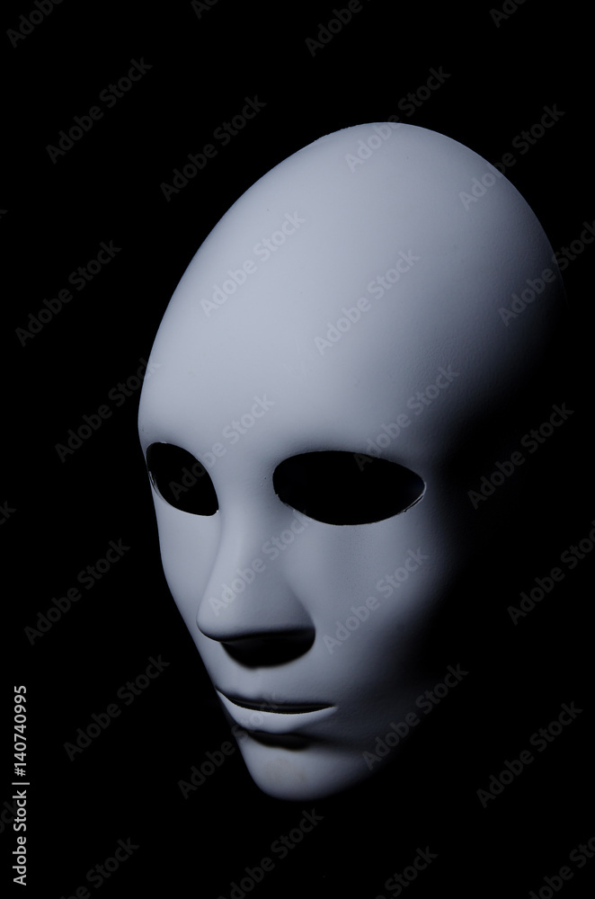 White mask with neutral expression and shadows on dark background