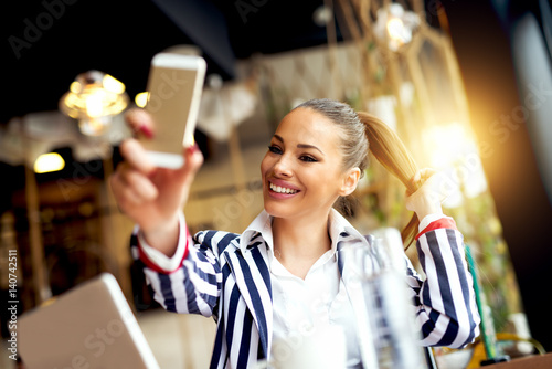 Tableau sur toile Beautiful woman in elegant suit taking selfie on phone