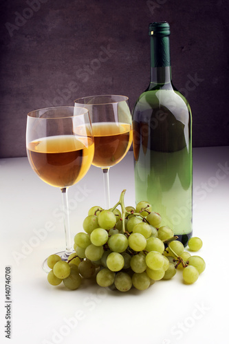 Bottle of white wine, grape on wooden table