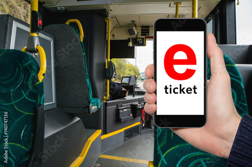 Hand with phone on the background of the city bus. The idea for the app purchase an e-ticket for public transport