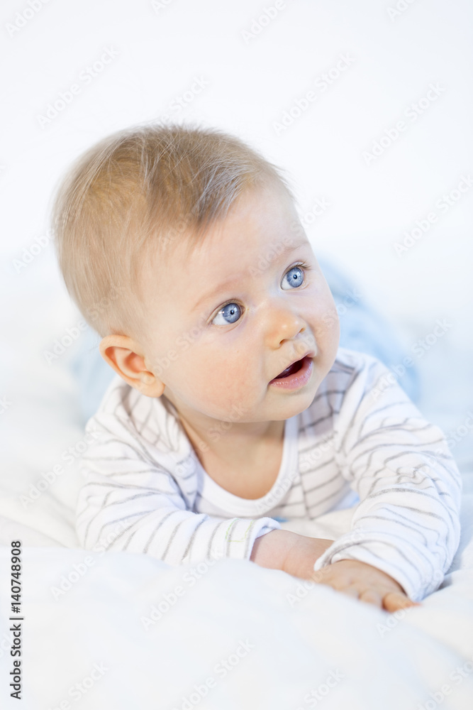 beautiful baby boy lying in bed on white background