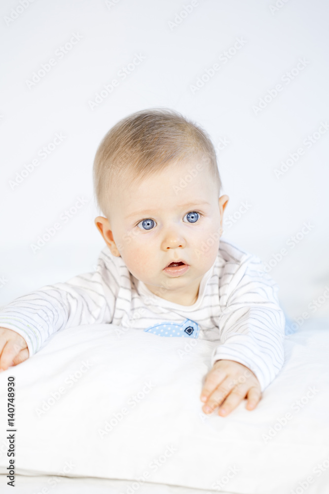 beautiful baby boy lying in bed on white background