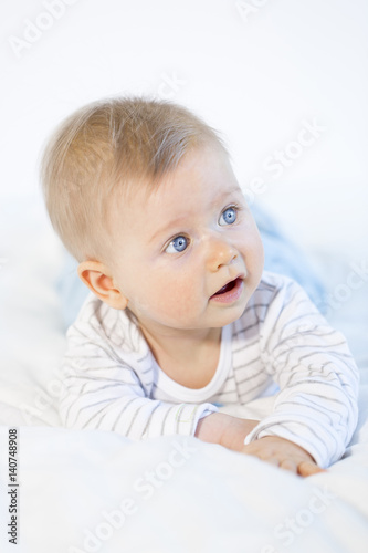 beautiful baby boy lying in bed on white background © epiximages