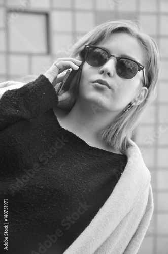 Successful young business woman in glasses is speaking by phone