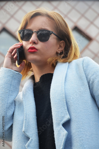 Successful young business woman in glasses is speaking by phone