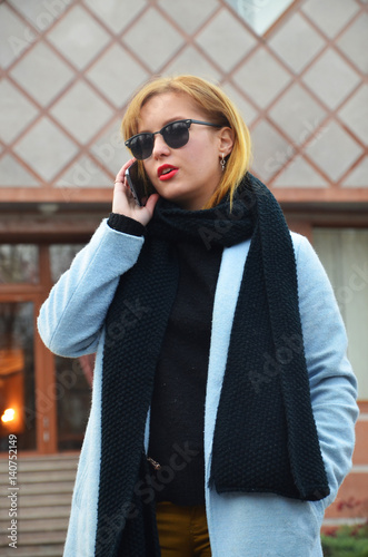 Successful young business woman in glasses is speaking by phone
