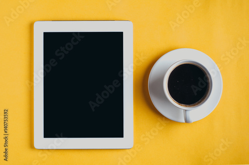 Tablet PC and coffee Cup on yellow background © alekseyliss