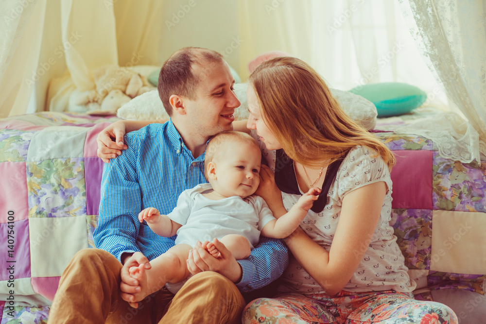 Joyful parents hug each other holding their little son