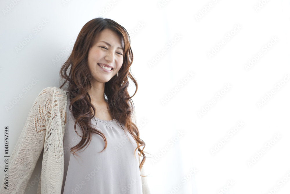 Young woman smiling by window, copy space Young woman smiling by window, copy space