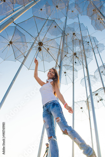 Girl holding an umbrella. Installation Flying umbrellas, Greece. Group of umbrellas on blue sky background. Concept of summer travel. Umbrellas in Thessaloniki, Greece. 
