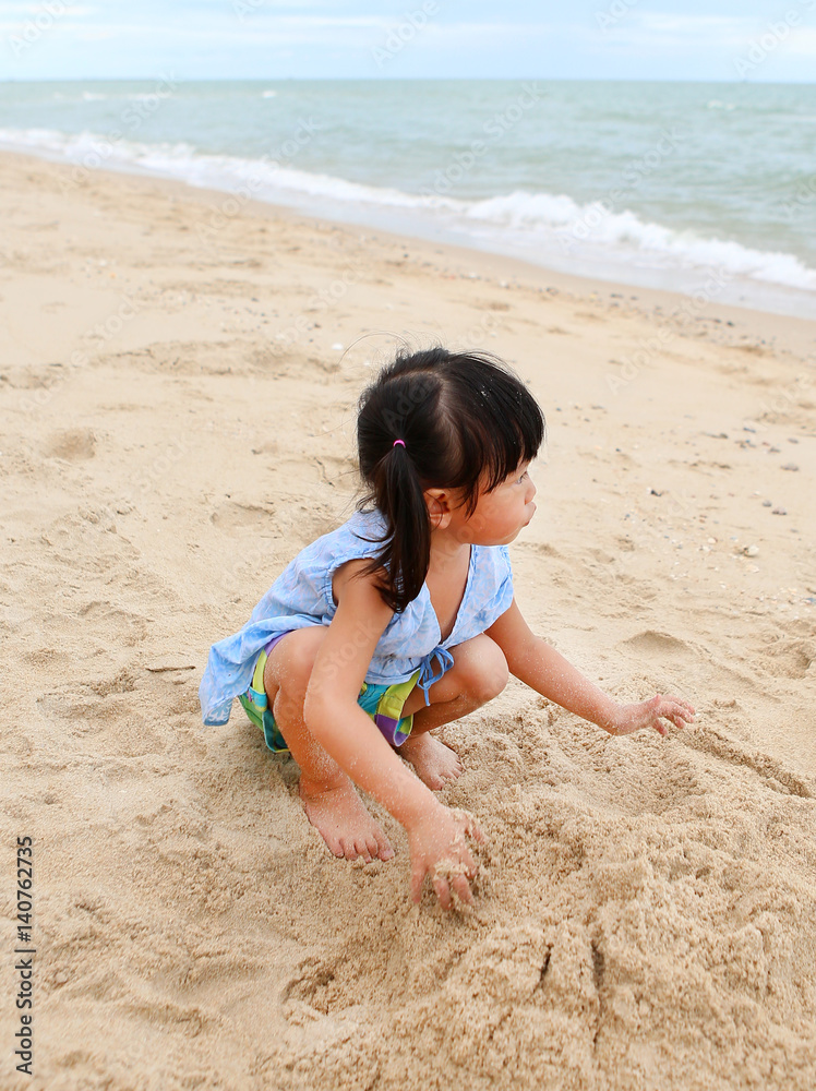 Cute child girl playing sand at the beach