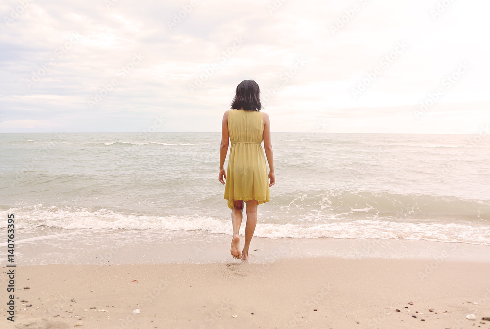 Young woman walking alone on the beach, go straight to the sea Young woman walking alone on the beach, go straight to the sea