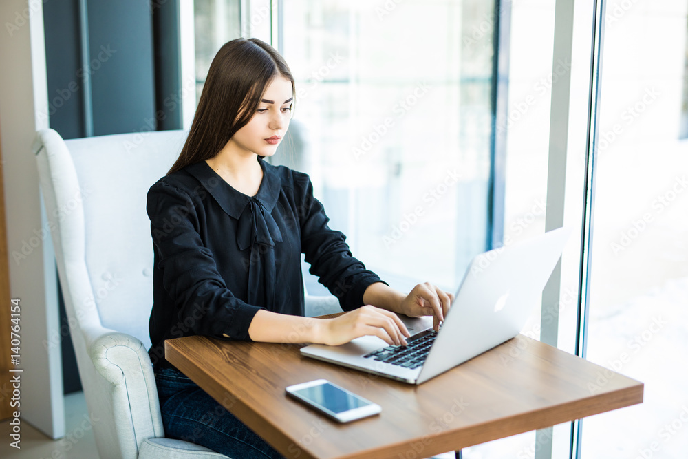 Female working on laptop in a cafe. Female working on laptop in a cafe.
