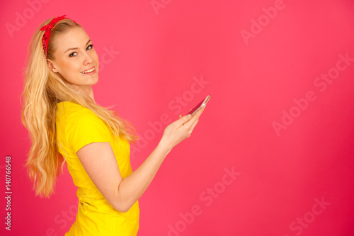 Young blond teenage girl in yellow t shirt surfing the web on smart phone