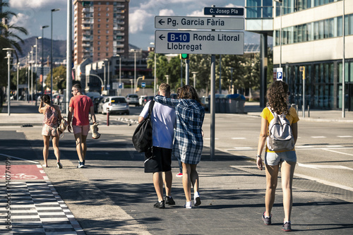 Group of young people are walking along the street on sunny day in Barcelona, Spain