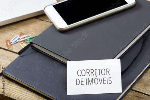 Corretor de imoveis, Portuguese text for Realtor business card on office desktop with electronic devices photo