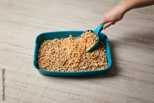 Fototapeta Naklejka Na Ścianę i Meble -  Female hand cleaning cat litter box on wooden background