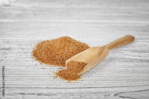 Wooden scoop and heap of coconut sugar on white background