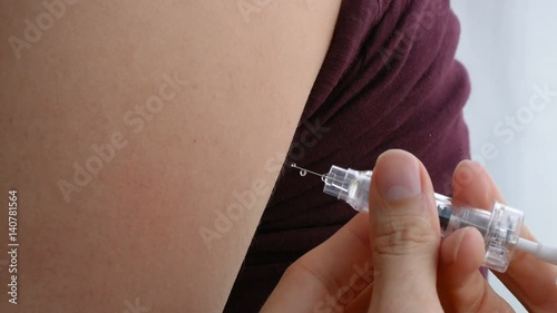 Closeup of giving an intramuscular anticoagulant injection into the arm using a safety syringe.