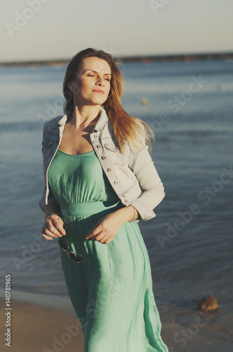 Amazing young woman in green dress near the sea