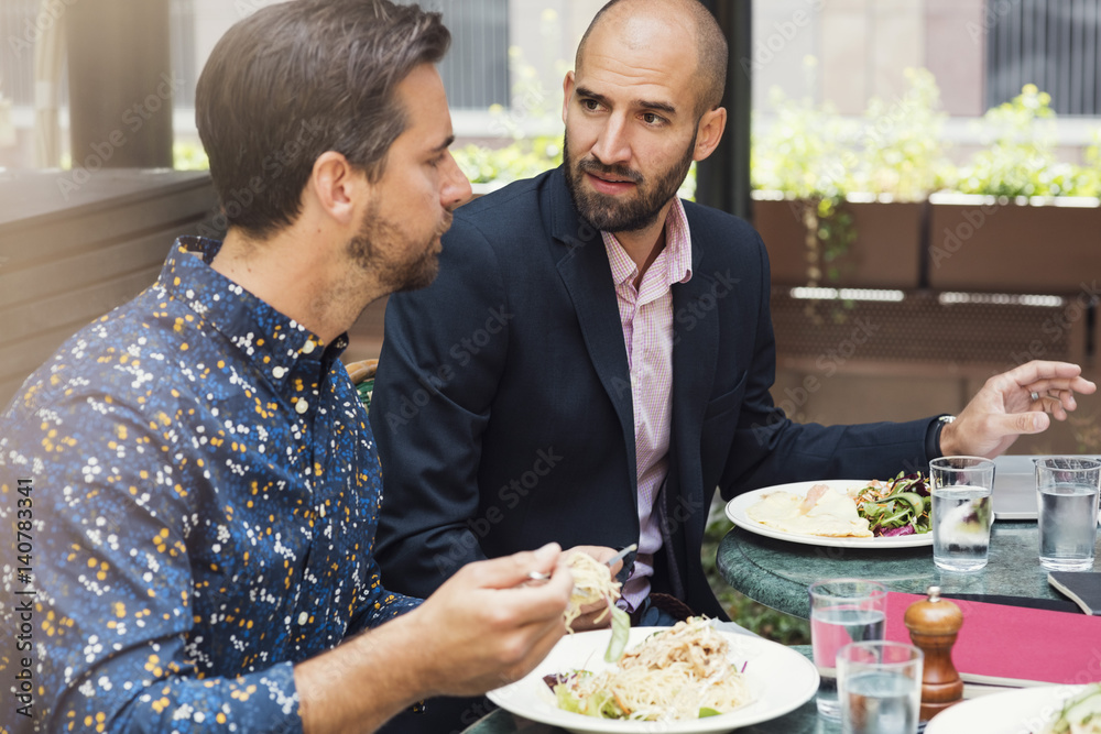 Mid adult businessmen discussing while having lunch at office yard Mid adult businessmen discussing while having lunch at office yard