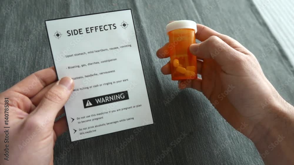 Holding a side effect warning label and a pill bottle in the other hand.