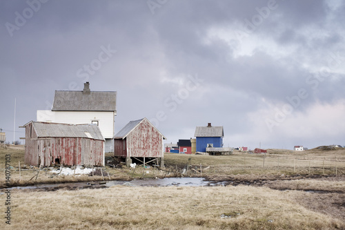 Old houses in field against cloudy sky
