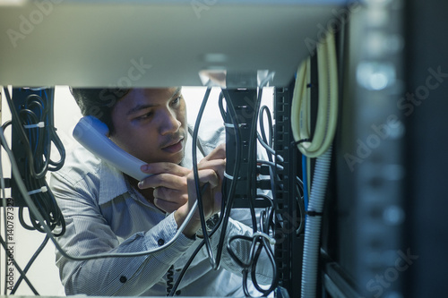 Man troubleshooting in data centre with consult by telephone