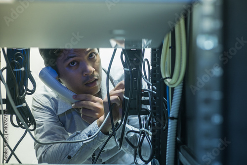 Man troubleshooting in data centre with consult by telephone