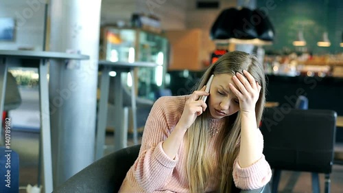 Girl sitting in the cafe and receiving bad news while having a call on cellphone
 photo