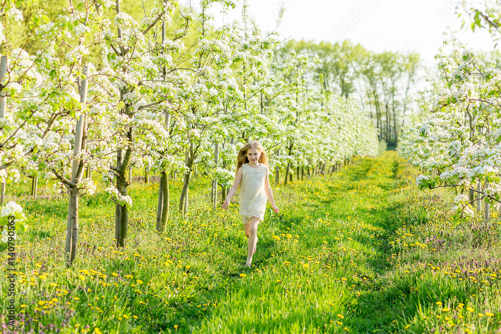 A beautiful little girl runs through a flowering garden in the spring A beautiful little girl runs through a flowering garden in the spring