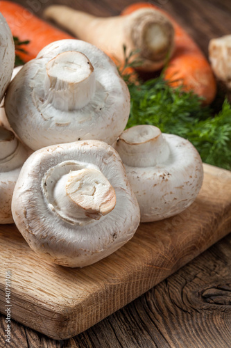Champignon mushrooms on a wooden cutting board.