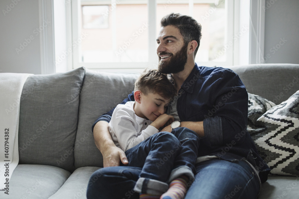 Happy father and son while sitting on sofa at home Happy father and son while sitting on sofa at home