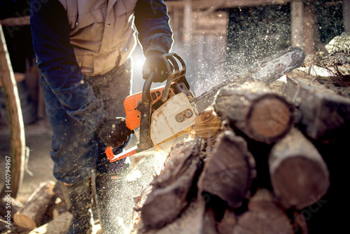 Chainsaw in action cutting wood. Man cutting wood with saw, dust and movements.