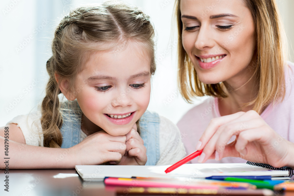 Happy mother and daughter drawing at home Happy mother and daughter drawing at home