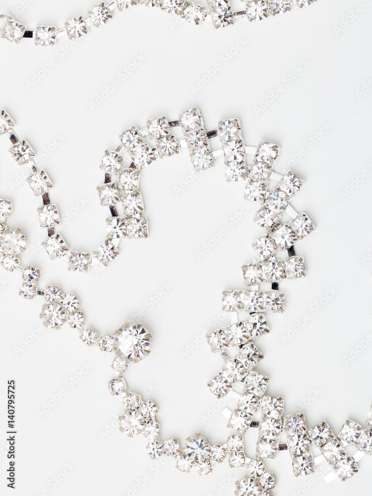 A beautiful diamond halo and white gold pendant dangles from a chain. Fine Jewelry necklace isolated on a white background with shadow and reflection
