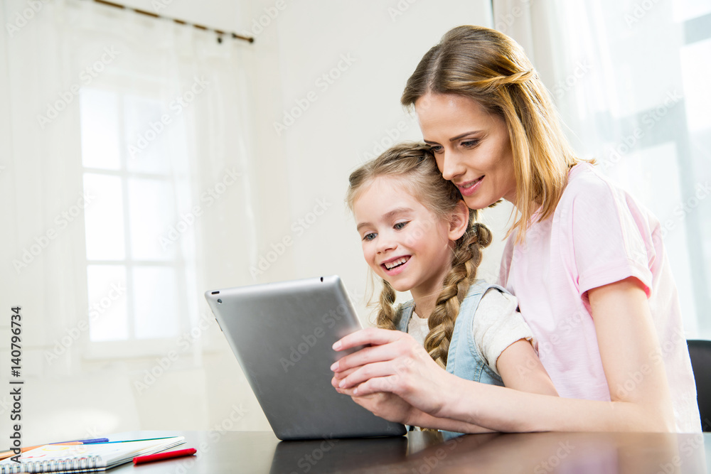 Happy mother and daughter using digital tablet at home Happy mother and daughter using digital tablet at home