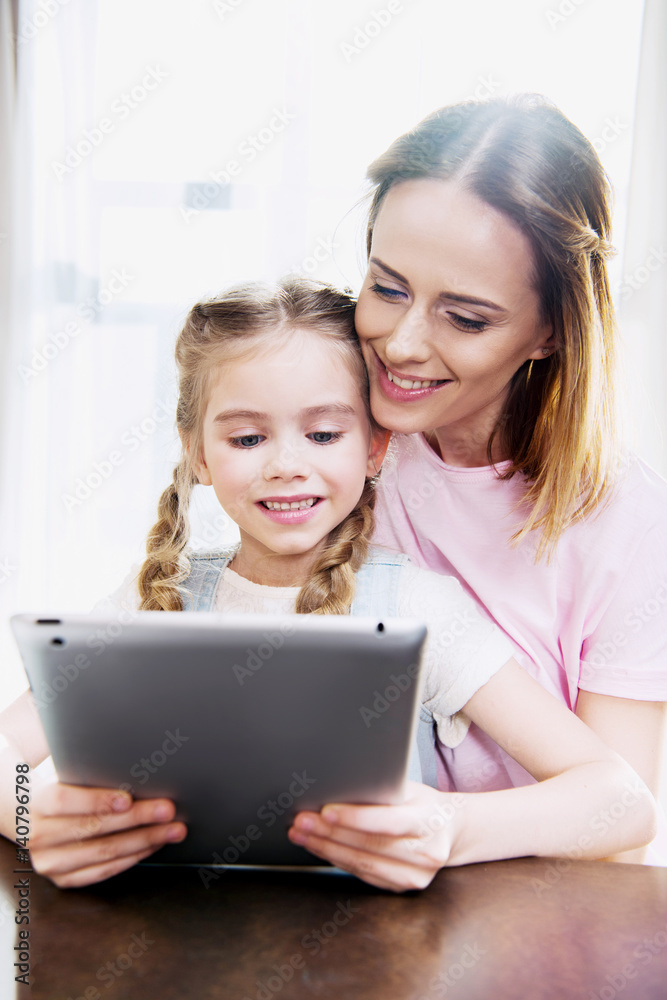 Happy mother and daughter using digital tablet at home Happy mother and daughter using digital tablet at home