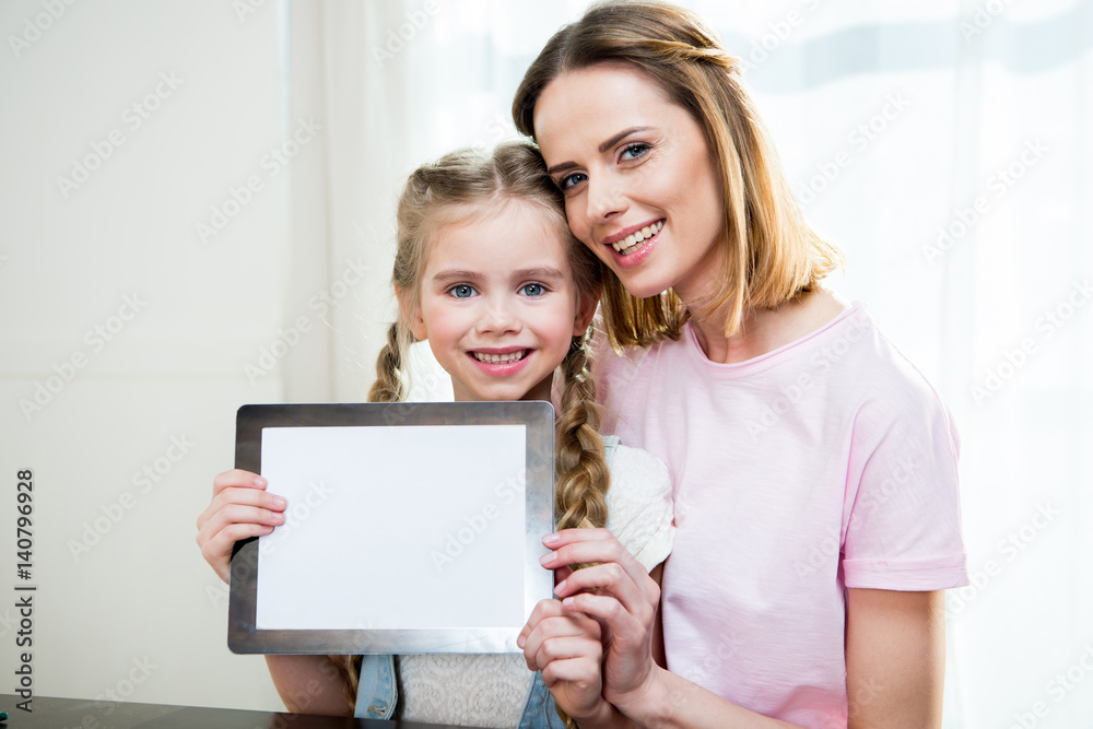 Happy mother and daughter showing digital tablet at home Happy mother and daughter showing digital tablet at home