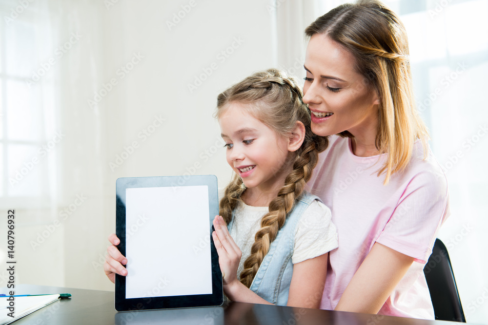 Happy mother and daughter showing digital tablet at home Happy mother and daughter showing digital tablet at home