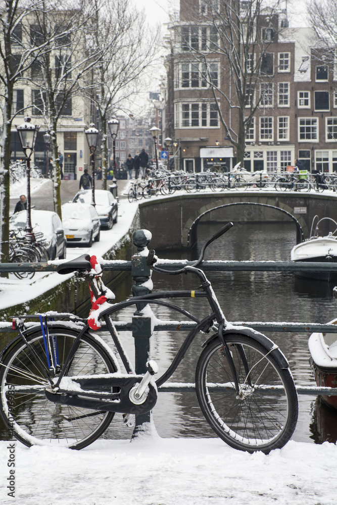 Usual black bike on the bridge near the canal in Amsterdam in winter